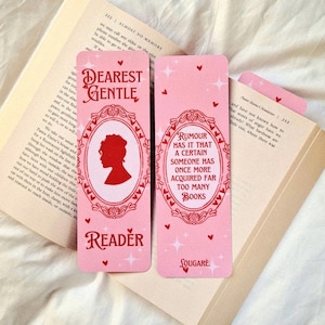 May include: Two pink bookmarks with text and illustrations. One says "Dearest Gentle Reader" with a silhouette and ornate frame. The other says "Rumour has it that a certain someone has once more acquired far too many books."