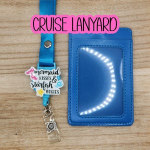 May include: A blue lanyard with a matching cardholder. The lanyard has a charm that reads "mermaid kisses & starfish wishes." The text "CRUISE LANYARD" is in a pink rectangle at the top.