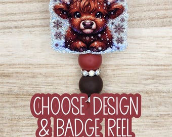 May include: A badge reel featuring a square glittery topper with a brown Highland cow illustration surrounded by snowflakes. Below the topper are two round beads, one red and one dark brown, separated by a silver rhinestone spacer.