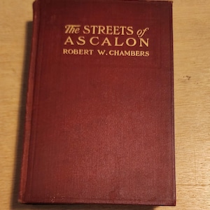 May include: A burgundy hardcover book with gold lettering on the front cover. The title is "The Streets of Ascalon" by Robert W. Chambers.