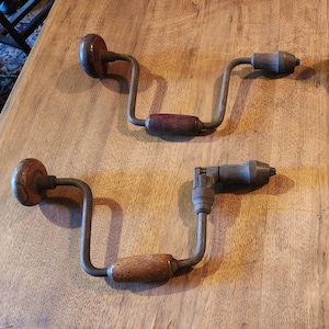 Puede incluir: Dos taladros de manivela antiguos con mangos de madera. Los taladros son de metal y tienen un aspecto vintage.
