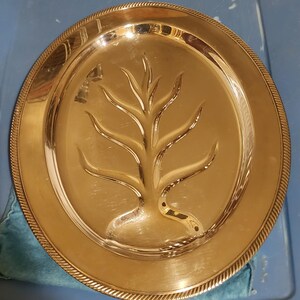 May include: A silver oval serving platter with a raised tree design in the center. The platter has a beaded edge.