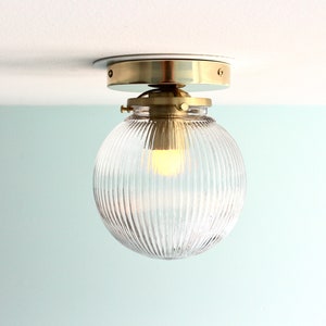 May include: A brass ceiling light fixture with a clear, ribbed glass globe shade.