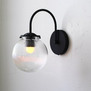 Wall Sconce Lamp, Black Curved Arm Mid Century Modern Wall Mounted Lighting Fixture, Clear Ribbed Glass Bubble Globe, Wire-In or Plug-In
