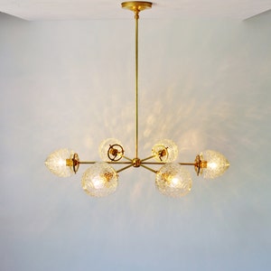 May include: A gold chandelier with six clear glass globe shades. The chandelier has a simple, modern design.