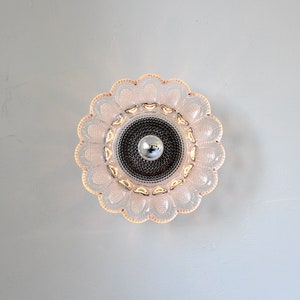 May include: A pink glass ceiling light fixture with a flower-shaped design and a silver center.