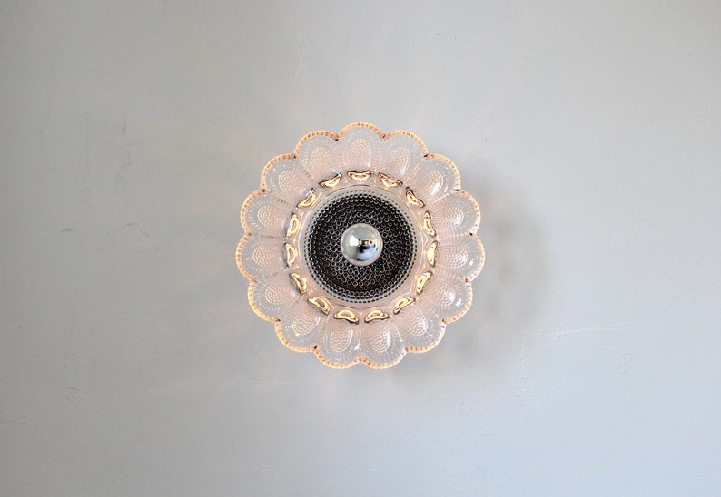 May include: A pink glass ceiling light fixture with a flower-shaped design and a silver center.