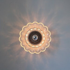 May include: A clear glass ceiling light fixture with a flower-shaped design. The light is on and casting a warm glow.