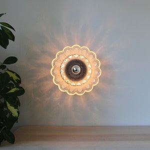 May include: A clear glass ceiling light fixture with a scalloped edge and a chrome center. The light is on and casting a warm glow.