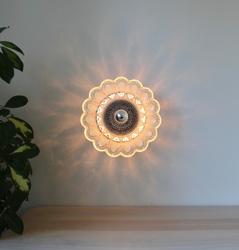 May include: A clear glass ceiling light fixture with a scalloped edge and a chrome center. The light is on and casting a warm glow.