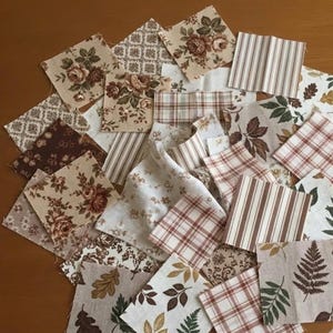 Könnte beinhalten: Eine Sammlung von Stoffquadraten in verschiedenen Mustern und Farben. Die Quadrate zeigen Blumen-, Streifen-, Karo- und Blattmuster in Braun-, Beige- und Cremetönen. Ideal für Quilt- oder Bastelprojekte.