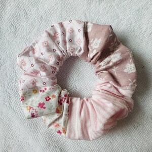 Può includere: Un elastico per capelli fatto a mano con un design patchwork. Presenta motivi floreali e geometrici nei toni del rosa, bianco e malva. Questo accessorio per capelli è progettato per raccogliere e tenere i capelli ed è adatto a varie acconciature.