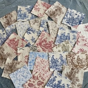 Op de afbeelding: Een verzameling kleine, vierkante stofstukken met diverse toile-patronen in blauw, rood en bruin op een crèmekleurige achtergrond. De ontwerpen omvatten bloemmotieven, pastorale scènes en andere decoratieve elementen. Ideaal voor knutselen.