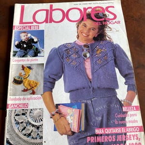 May include: A vintage January 1989 issue of Labores del Hogar magazine featuring a cover with a person wearing a purple knit cardigan, blue jeans, and holding books. The cover includes images of a baby, a duck craft, and crochet patterns.