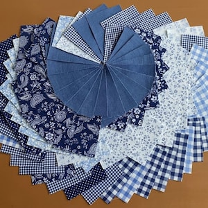 Puede incluir: Una disposición circular de muestras de tela azul. Las telas incluyen patrones de mezclilla, cachemira, floral, cuadros y lunares. Las muestras están dispuestas radialmente, mostrando la variedad de texturas y diseños.