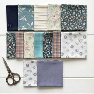 May include: A collection of fabric squares in various floral, plaid, and solid patterns. Colors include navy, teal, peach, and white. A pair of vintage scissors is placed near the fabric squares.