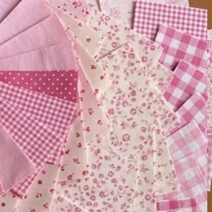 Op de afbeelding: Een verzameling roze stoffen vierkanten met diverse patronen. Inclusief effen roze, stippen, ruitjes en bloemenprints. Geschikt voor patchwork of knutselprojecten. Metrische maten.
