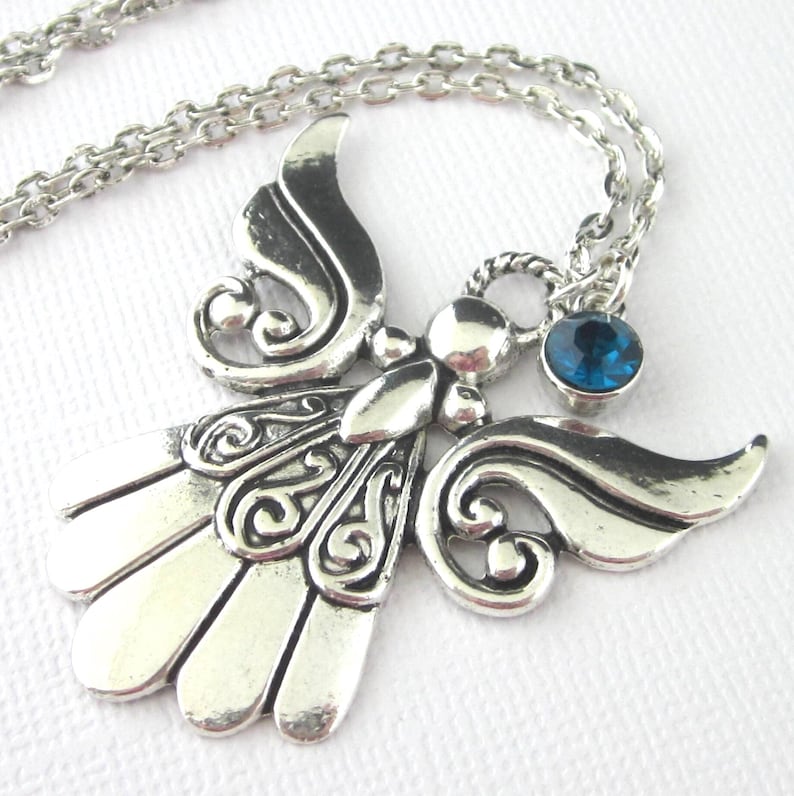 Antiqued silver, textured large angel pendant necklace with birthstone charm. Steel necklace chain 19 inches long. Angel pendant 1 5/8  by 1 5/8 inches.  Glass charm set in antiqued silver setting, 6mm.  Back of pendant is concave with a pattern.
