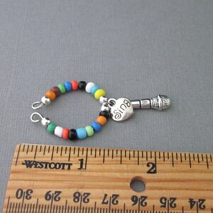 May include: A colorful beaded charm bracelet with a silver microphone charm and a heart charm that says "Sing".