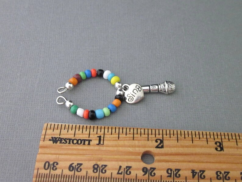 May include: A colorful beaded charm bracelet with a silver microphone charm and a heart charm that says "Sing".