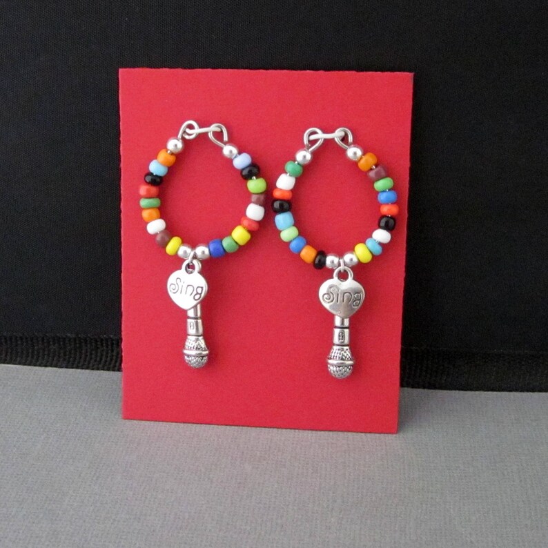 May include: A pair of colorful beaded hoop earrings with a silver microphone charm and a heart-shaped pendant that says "Sing".