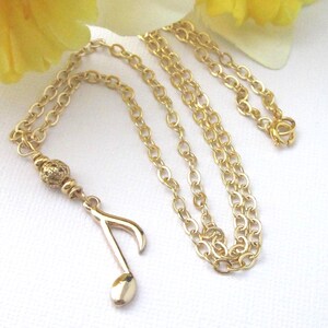 Small gold plated 8th note charm dangles from a gold filigree bead. The full length of the pendant is 1 3/4 inches long.  Comes with a shiny gold plated flat cable chain. Choose 19, 18, or 17 inches long.
