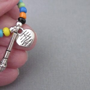 May include: A colorful beaded bracelet with a silver heart charm and a silver microphone charm.