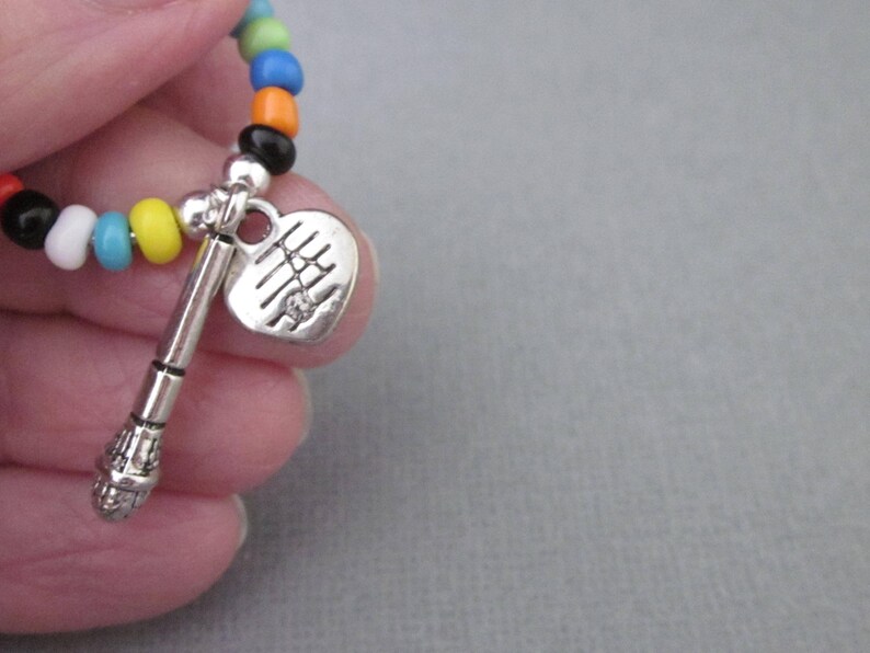 May include: A colorful beaded bracelet with a silver heart charm and a silver microphone charm.
