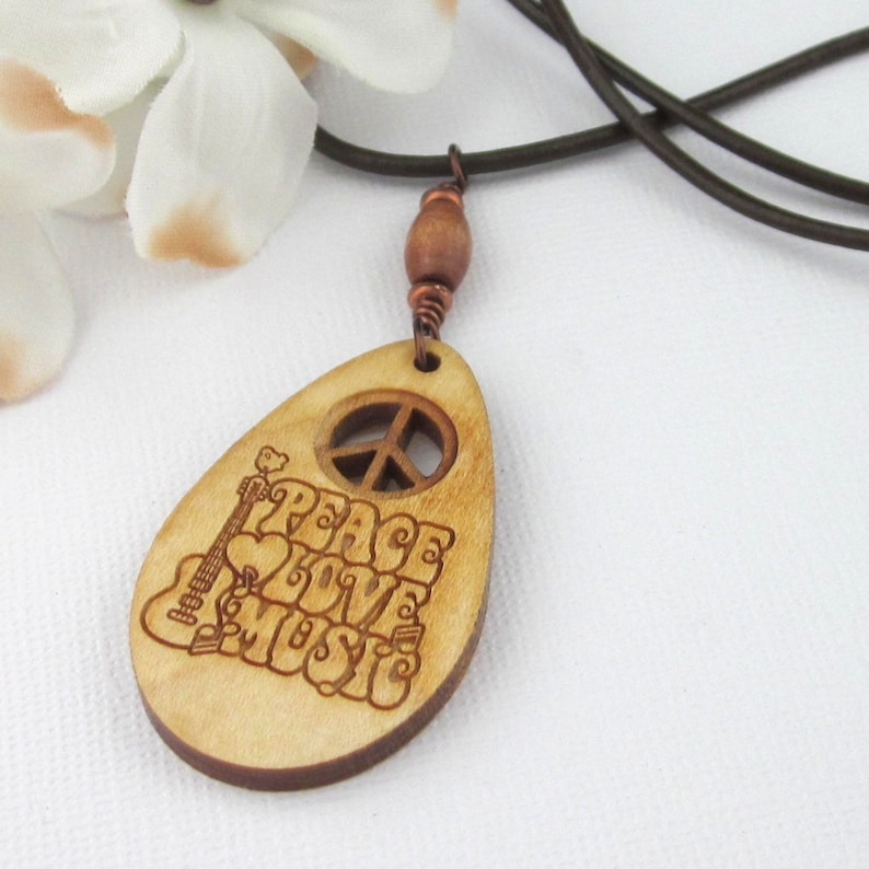 Wood pendant with open cut through peace sign and etched words peace, love, music, along with an acoustic guitar. Wood bead above pendant.  Brown leather cord, 22 inches long.  Wood pendant length with bead 2 5/8 inches. Rare and unique.
