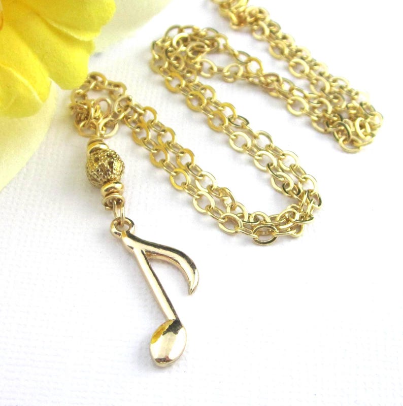 Small gold plated 8th note charm dangles from a gold filigree bead. The full length of the pendant is 1 3/4 inches long.  Comes with a shiny gold plated flat cable chain. Choose 19, 18, or 17 inches long.