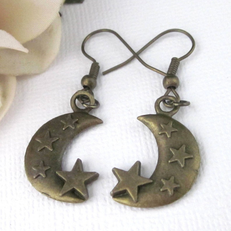 Antiqued brass crescent moon earrings with raised stars. Charms are double sided. Antiqued brass ear wires. Length 1 5/8 inches, moon charms 22mm x 15mm