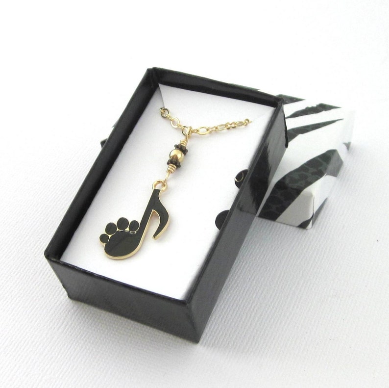 Black and Gold both 8th note and animal paw print necklace Gold plated chain. Paw print dangles from a section of one gold bead and two daisy spacers.  Measures  1 3/4  inch  x 5/8 inch wide. Choose chain length 15 thru 18 inches. Gift box included.