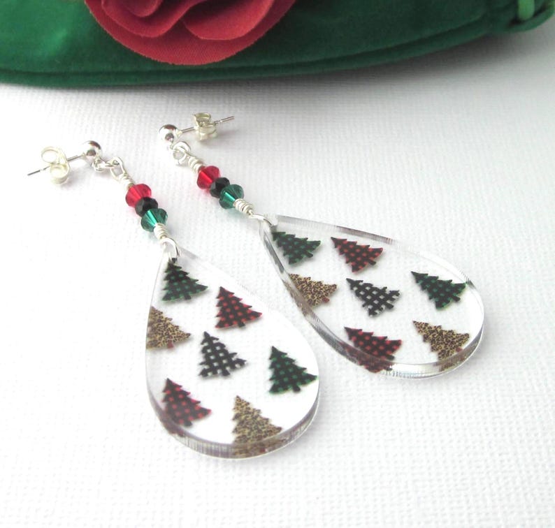 Acrylic teardrop shape drops have Christmas trees with buffalo plaids and leopard prints. Sparkling red, green and black crystals and sterling silver posts and clutches. Green velour gift pouch included.  Earrings dangle 2 5/8 inches long.  The acrylic teardrop alone 1 ½ inches long x 7/8 inch wide x 1/8 inch thick. Prestige crystal bicones 4 mm. Glass rondells 3 mm x 2 mm.