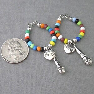 May include: Two colorful beaded bracelets with silver microphone charms and heart pendants that say "Sing".