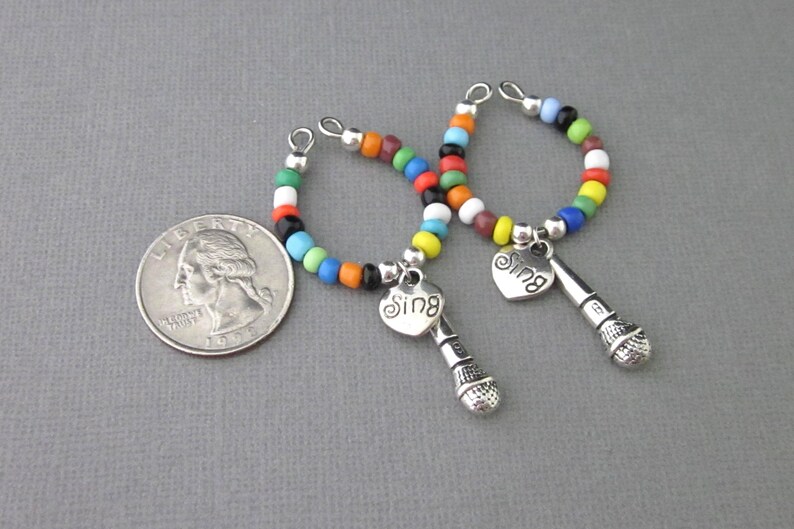 May include: Two colorful beaded bracelets with silver microphone charms and heart pendants that say "Sing".