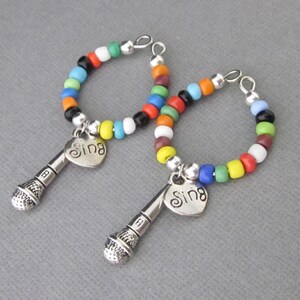 Wine glass charms with dimensional microphone and heart charm.  Heart has engraved word Sing. Beaded with multicolored seed beads. Bend to open and close around stem of wine glass. Great gift for karaoke party hostess. Mic charm 27 mm long.