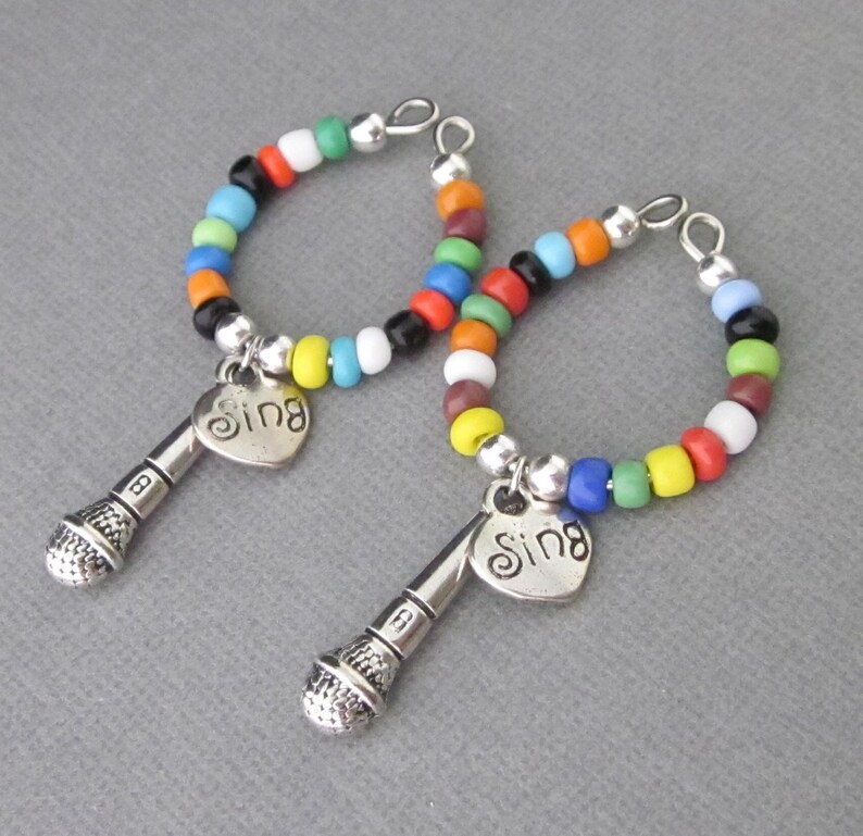 Wine glass charms with dimensional microphone and heart charm.  Heart has engraved word Sing. Beaded with multicolored seed beads. Bend to open and close around stem of wine glass. Great gift for karaoke party hostess. Mic charm 27 mm long.