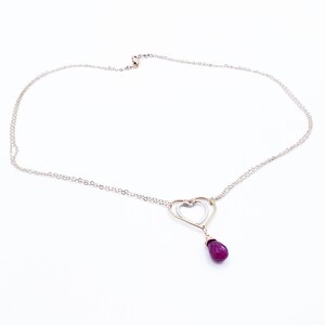 May include: A silver chain necklace with a double heart pendant and a dangling purple gemstone.