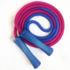 May include: A colorful jump rope with a pink and blue gradient. The rope is coiled, with two blue wooden handles. This fitness equipment is designed for exercise and fun.