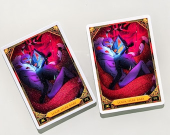 May include: Two rectangular trading cards featuring a vibrant illustration of two animated characters in a red and purple setting. The cards have a gold-toned decorative border and the text "LOOK HERE BABY" printed in a banner at the bottom.