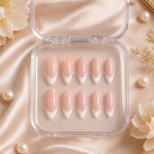 May include: A set of ten oval false nails in a clear plastic case. Each nail has a pale pink base with a white French tip. The nails are arranged in two rows of five.