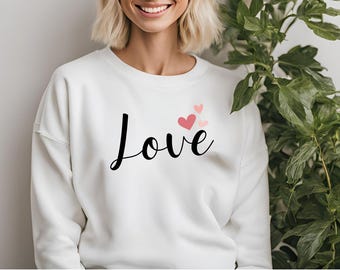 May include: White sweatshirt with the word "LOVE" in black script and pink hearts.