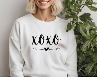 May include: White sweatshirt with the text "XOXO" in black script with a small heart underneath.