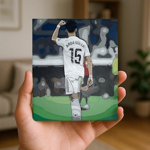 May include: A rectangular canvas print featuring a stylized illustration of a soccer player from behind, wearing a white jersey with the name ARDA GÜLER and the number 15 printed on the back. The player is shown on a green field with a dark background.
