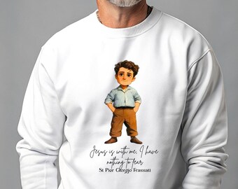 Puede incluir: Sudadera blanca con una ilustración de dibujos animados de un niño con una camisa a rayas azules y pantalones marrones. El texto "Jesus is with me. I have nothing to fear" y "St Pier Giorgio Frassati" está impreso debajo.