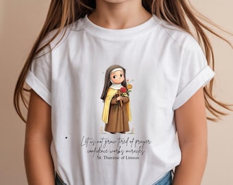 May include: White t-shirt featuring an illustration of St. Therese of Lisieux holding flowers and a cross. The image includes the text "Let us not grow tired of prayer, confidence works miracles, St. Therese of Lisieux."