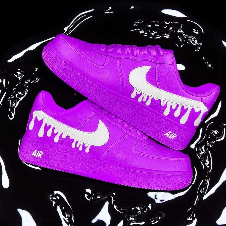 May include: Bright purple trainers with white Nike swooshes and dripping paint effect. The word "AIR" is printed on the side. The shoes are set against a black background with white liquid patterns.
