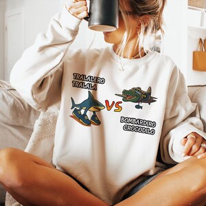 Camiseta Tralalero Tralala vs Bombardiro Crocodilo, Camiseta engraçada de batalha de tubarão e crocodilo, Camiseta de luta de animais de desenho animado, Camiseta de meme excêntrica