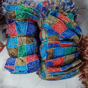 K&ouml;nnte beinhalten: Stapel bunter Stoff-Kopfbedeckungen mit geometrischen Mustern in Rot, Blau, Gr&uuml;n und Braun. Die Kopfbedeckungen sind gefaltet und geb&uuml;ndelt, einige mit dekorativen Fransen.