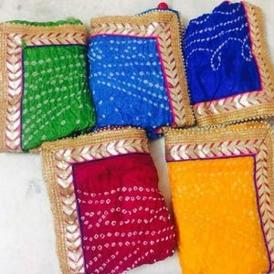 K&ouml;nnte beinhalten: Eine Sammlung farbenfroher, gemusterter Textilien. Die Stoffe sind in Gr&uuml;n-, Blau-, Rot- und Gelbt&ouml;nen gehalten und weisen ein wei&szlig;es Punktmuster auf. Jedes St&uuml;ck hat einen Gold- und Silberrand.